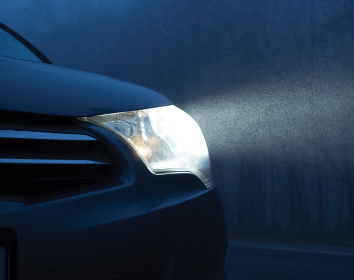 Headlight of car shining through fog at night