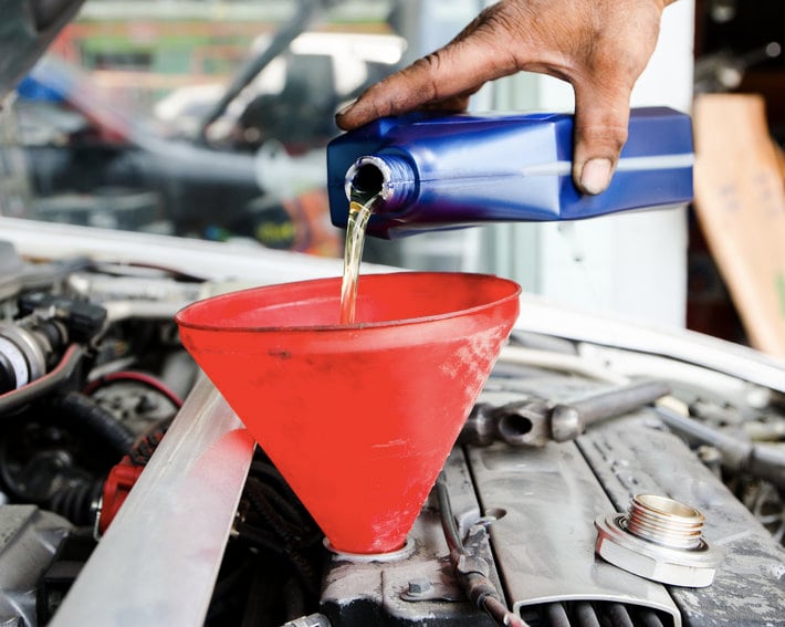 technician pouring new motor oil into vehicle