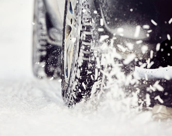 Back tire kicking up snow on winter road