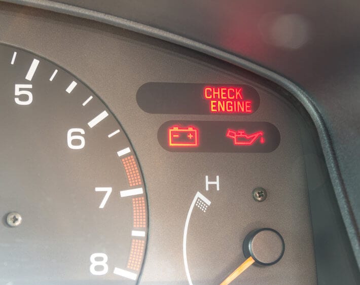 Close up of car dashboard with check engine light, oil light, and battery indicator lights on