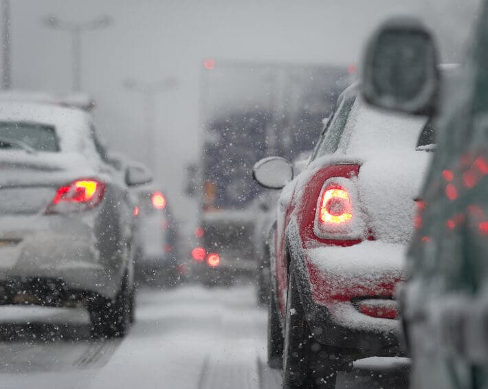 Cars sitting in traffic, driving in snowy conditions