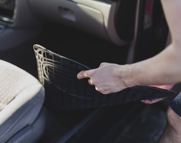 Person removing passenger side floormat for cleaning
