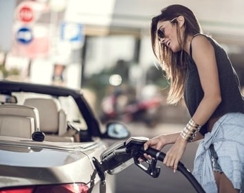 Woman in sunglasses pumping gas for into a convertible sedan