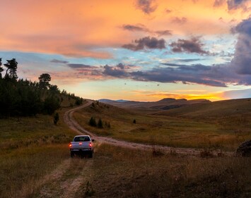 Pick up truck on country backroad during sunset 