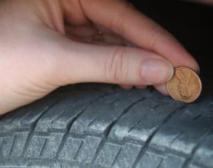 Person putting a penny into tire tread