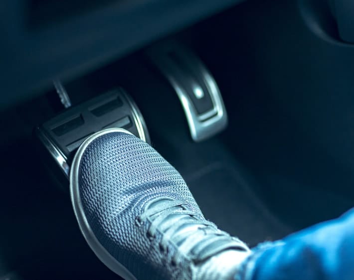 sneaker-wearing foot on brake pedal