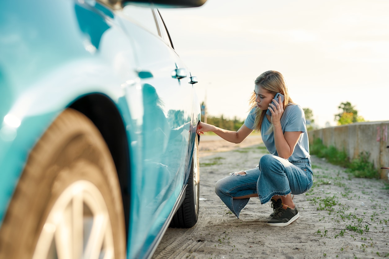 image of a woman looking at a flat tire